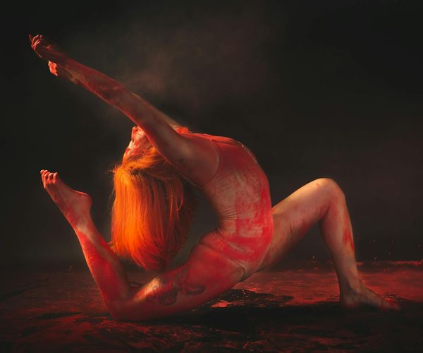 Silhouette of a person in a dynamic yoga pose against a sunrise.